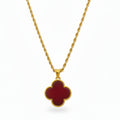 Gold necklace with a red clover-shaped pendant on a white background