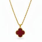 Gold necklace with a red clover-shaped pendant on a white background