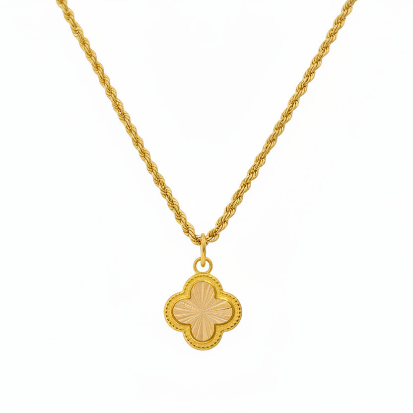 Gold necklace with a four-leaf clover pendant on a white background