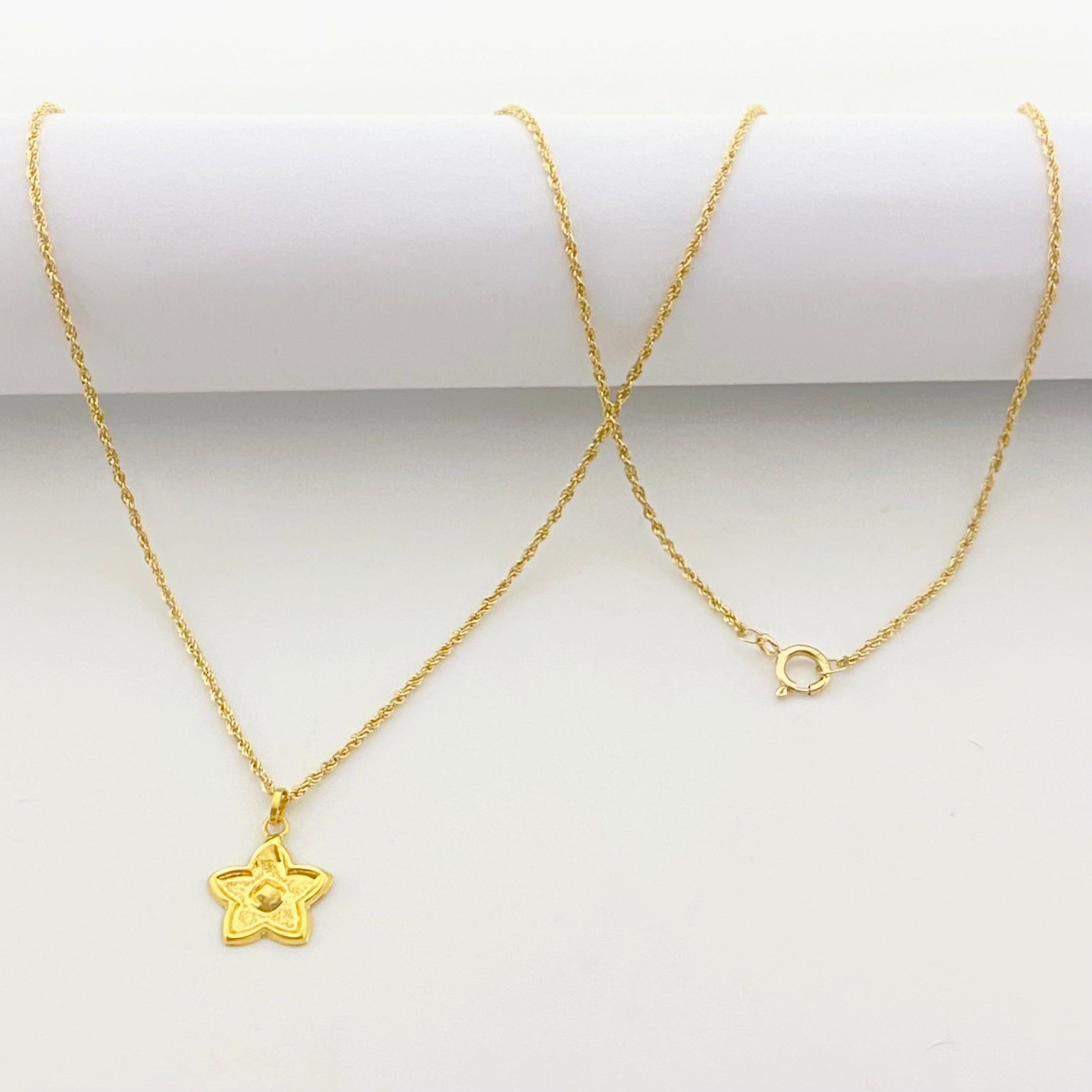 Gold necklace with a star pendant on a white background