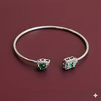 Silver bracelet with green gemstones on a maroon background