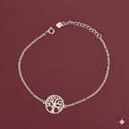 Silver bracelet with a tree of life design on a maroon background