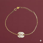 Gold bracelet with a diamond-studded clasp on a maroon background