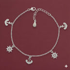 Silver bracelet with anchor and wheel charms on a red background