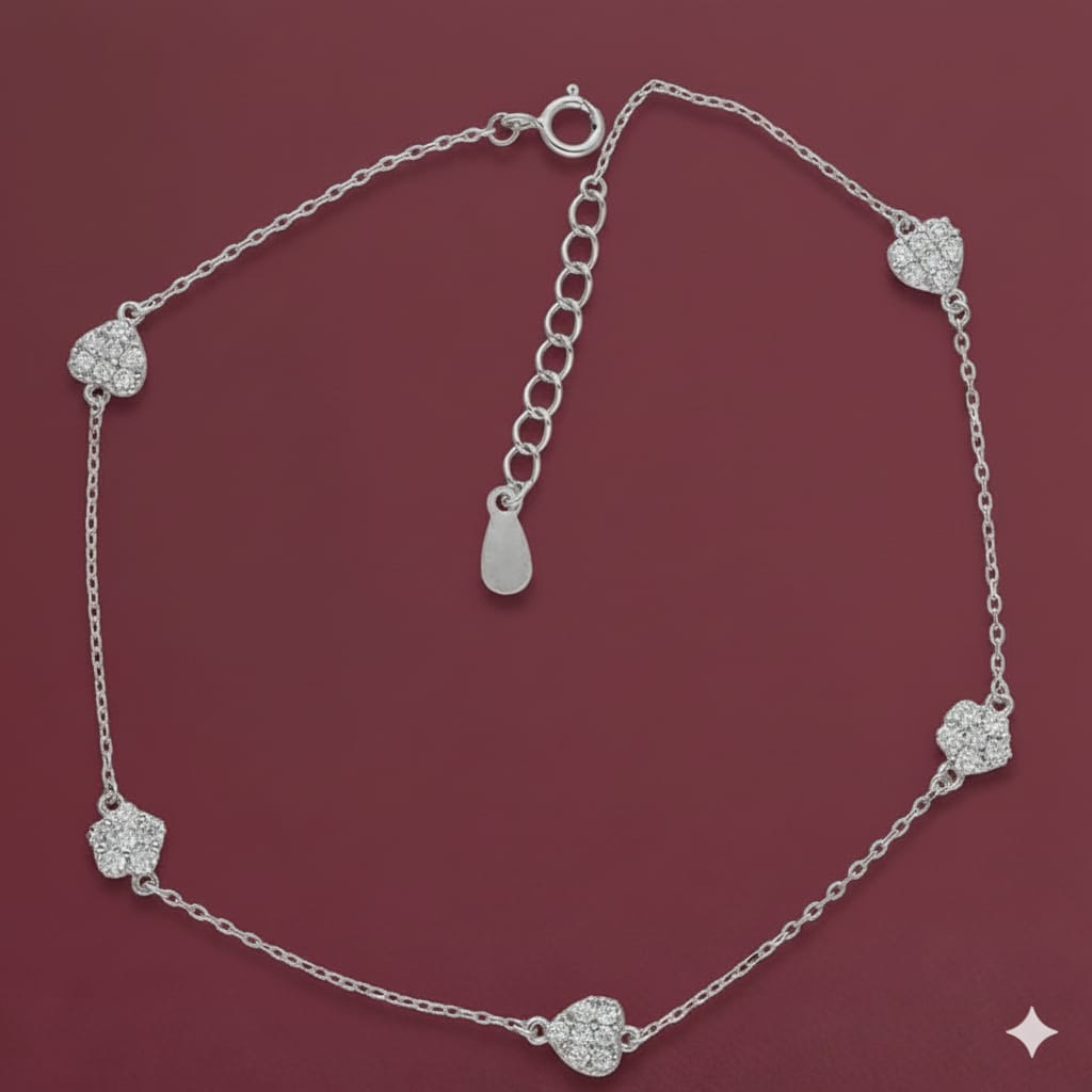Silver anklet with heart-shaped charms on a maroon background