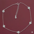 Silver anklet with heart-shaped charms on a maroon background