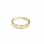 Gold ring with cut-out design on a gray background