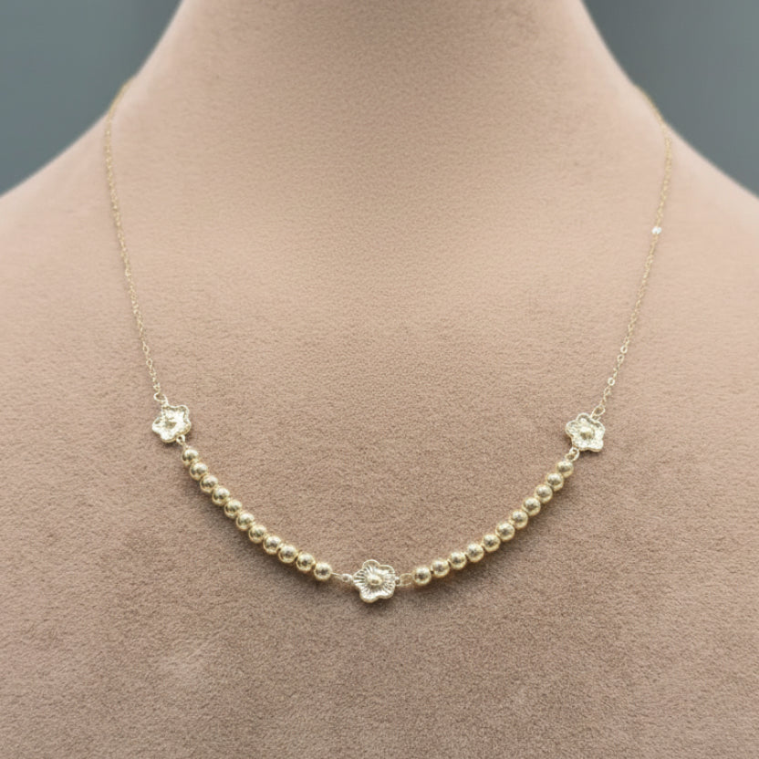 Gold necklace with floral clasp on a mannequin bust, close-up inset showing necklace details.
