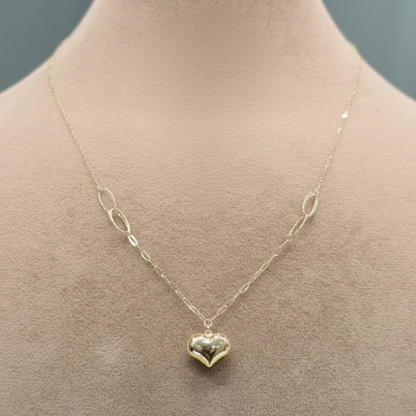 Gold heart-shaped pendant necklace on a mannequin with close-up detail.