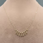 Gold necklace with small beads on a mannequin, close-up inset showing necklace details.