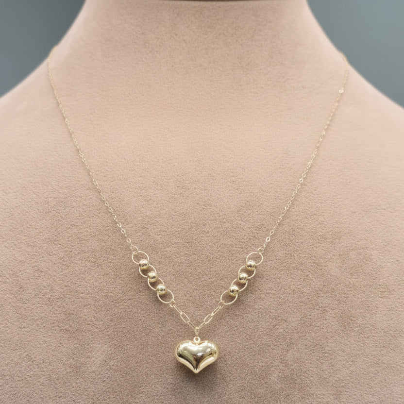Gold necklace with a heart pendant on a mannequin, labeled with weight and code.