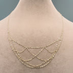 Gold necklace on a mannequin with weight and code information displayed.