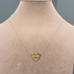 Gold necklace with a heart-shaped pendant on a mannequin.