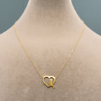 Gold necklace with a heart-shaped pendant on a mannequin.