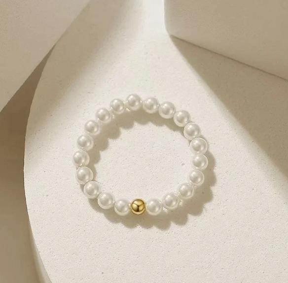 Pearl bracelet with a gold bead on a light beige background