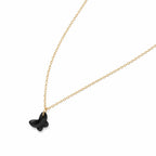 Black butterfly pendant on a gold chain against a white background