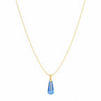 Gold necklace with a blue teardrop pendant on a white background