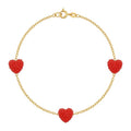 Gold bracelet with red heart-shaped charms on a white background
