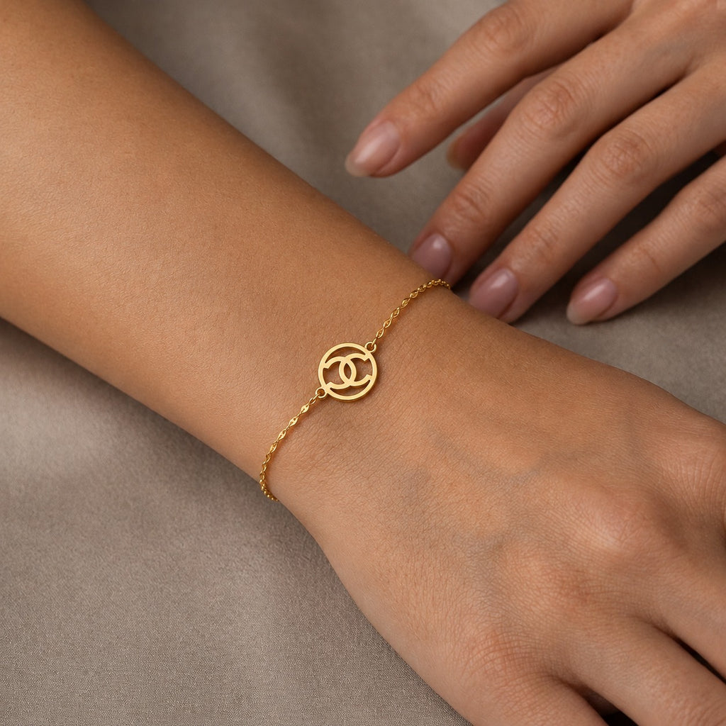 Gold bracelet on a wrist with a neutral background
