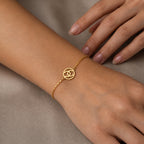 Gold bracelet on a wrist with a neutral background