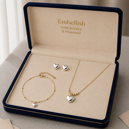Gold jewelry set with heart-shaped charms in an 'Embellish' jewelry box.