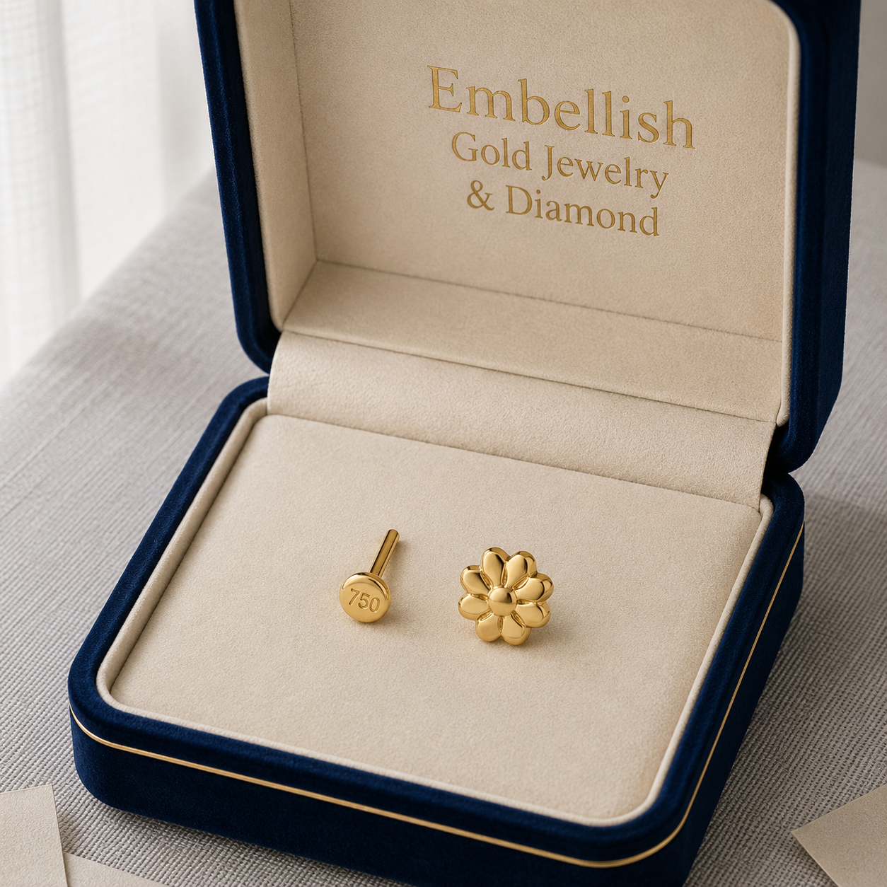 Gold earrings in a 'Embellish Gold Jewelry & Diamond' box on a light background